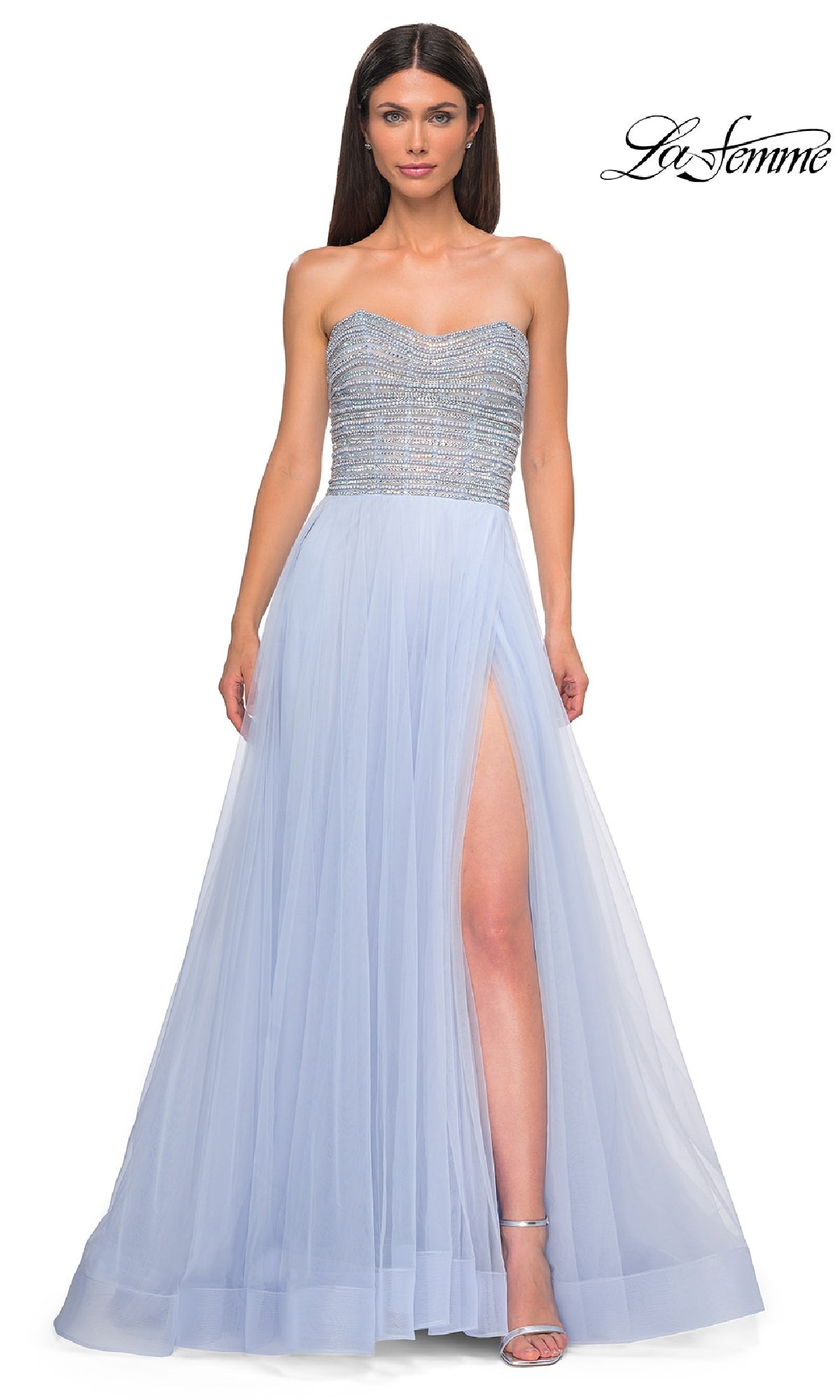 A woman models the Strapless Long Prom Ball Gown: La Femme 32875, featuring beaded details on the bodice and a light blue tulle skirt with a high slit, set against a white background.